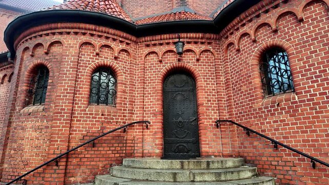 Brick church apse with semicircular arches wrought iron door and Romanesque architectural details on exterior facade