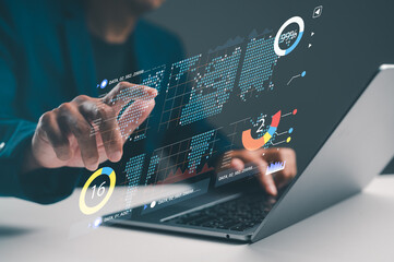 A person interacts with a transparent touchscreen, displaying data analytics and graphs on a laptop in a modern workspace.