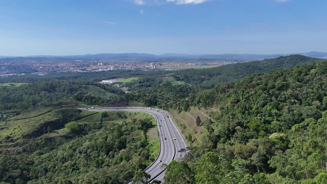 Rodovia atravessando a serra de Mogi das Cruzes no sentido do litoral, cercada por natureza, destacando mobilidade, turismo rodovi&aacute;rio e infraestrutura de acesso &agrave; praia