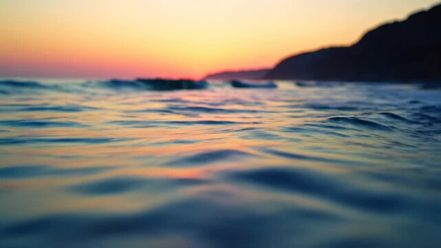 Golden sunset over ocean waves crashing on a sandy beach with dark silhouette of coastal cliffs in the background tranquil seascape