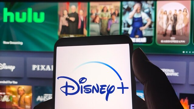Disney plus logo on smartphone in front of television streaming screen