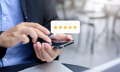 close up on businessman hand pressing on smartphone screen with gold five star rating feedback icon and press level excellent rank for giving best score point to review the service , business concept