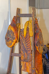Dry Delicatessen Cured Meat Dried Ham Slab of Bacon Hanging at Wooden Ladder