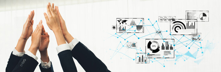 Business professionals express celebration and teamwork in a modern office setting, showcasing data charts and graphs that represent growth and innovation strategies. Trope