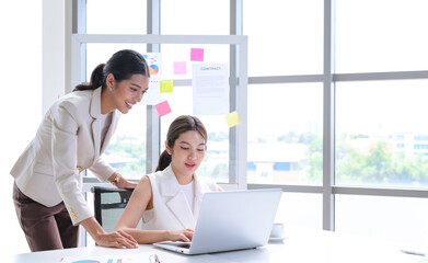 Attractive senior businesswoman train or mentor coach speaking to young woman. Two young Asian businesswomen working with laptop in the office.