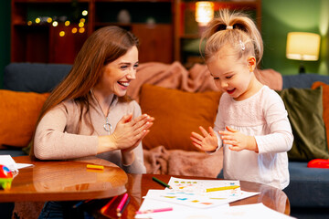 Fototapeta premium Mother and daughter playing and clapping hands, enjoying a happy childhood moment