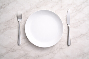 明るい白大理石のテーブルに白い皿とカトラリーを並べたフラットレイ背景