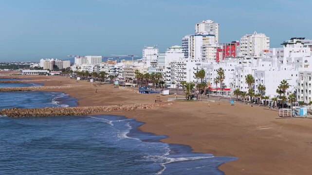 Golden Algarve Sunrise: Cinematic 4K Aerial of Quarteira Featuring Beachfront High-Rise Apartments, the Cal&ccedil;ad&atilde;o Promenade, and the Atlantic Horizon, Portugal