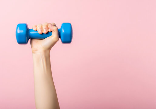 Raised arm gripping blue dumbbell against pink background, portraying fitness and exercise.