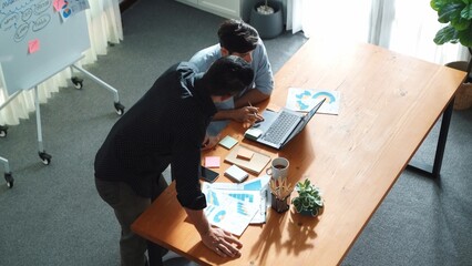 Top view of business team working together to analysis data by using laptop on meeting table. Diverse creative people discussing and brainstorming plan while looking at financial graph. Convocation.