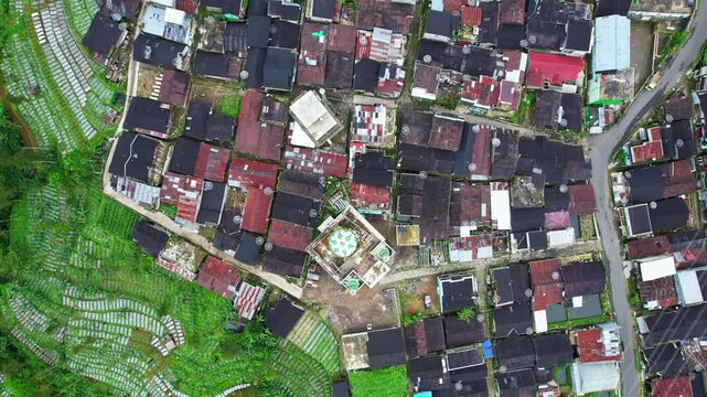 Aerial drone footage on top of a wonderful local village, and a beautiful green mosque in the middle , in the famous valley of Swiss van Java , Indonesia, seeing all the small streets and paths