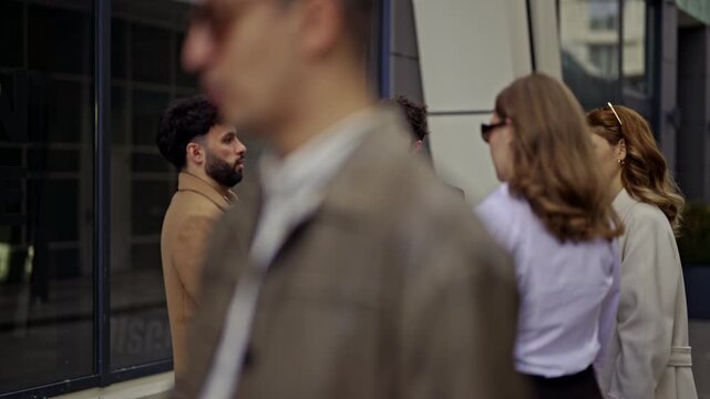 A group of diverse business people engage in a productive discussion outside an office building, highlighting the flexibility of remote work and collaborative efforts in an urban environment.