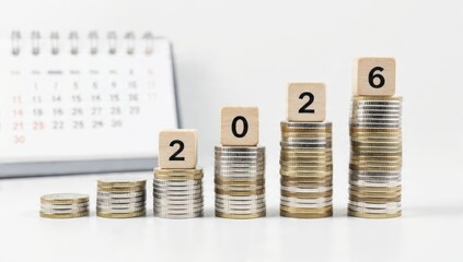 Stacks of growing Euro coins and wooden blocks spelling 2026 on a white background, symbolizing financial growth, investment strategy, budgeting, and future planning.