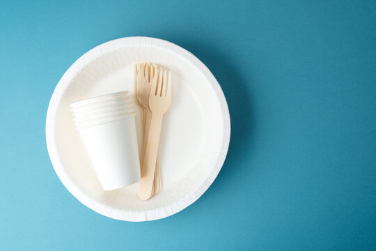 Closeup of white paper cups and wooden forks on eco-friendly plate