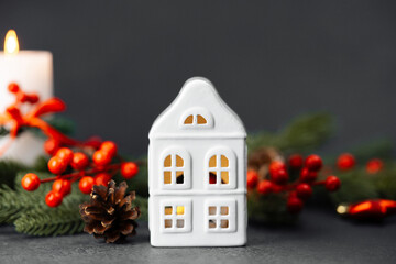 White ceramic house lantern with candle and pinecone, festive holiday decor, warm glowing light
