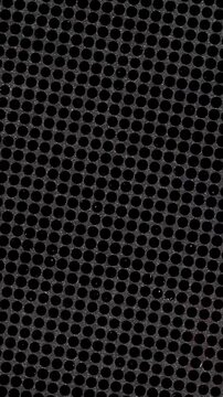 Close up of a dark metal speaker grill with round holes
