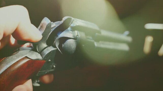 A revolver in a man's hand. With the hammer being engaged, readying the firearm for shooting.