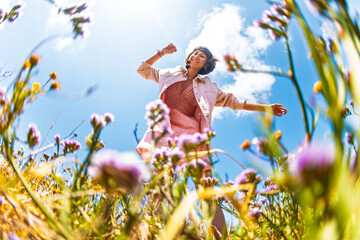 Happy woman enjoying nature outdoors among flowers. Outdoors.