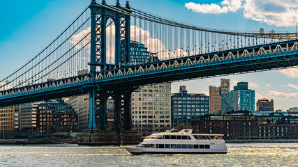 Boat passing under Manhattan Bridge. A white boat sails along the East River under the Manhattan Bridge in New York.