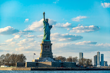 Fototapeta premium Statue of Liberty with blue sky in the background. The Statue of Liberty stands with the blue sky and white clouds behind it.