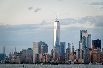 Naklejka premium One World Trade Center against cloudy Manhattan skyline. One World Trade Center rises above the Manhattan skyline under a cloudy sky.