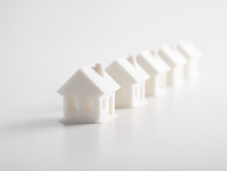 Miniature home prototypes lined up in row on white surface showing architectural design concepts and innovation