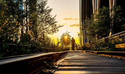 Fototapete Rund New York New York, USA, 8 August 2025: Cyclist at golden hour. Cyclist riding through golden hour light along the rails of Manhattan’s High Line.  © white78