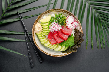 Tuna Poke Bowl with Fresh Red Radish and Avocado. A vibrant tuna poke bowl is presented with slices of fresh red tuna, avocado, cucumber, and colorful radish over white rice.