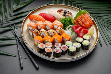 Diverse Platter of Sushi, Sashimi, and Maki Rolls. A circular platter presents a rich variety of nigiri, sashimi, and maki rolls, showcasing tuna, salmon, eel, and avocado fillings. © white78