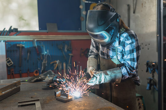 Woman welder successfully performing the MIG welding process in the family business workshop. Craftswoman, inspiration, and personal growth concepts.