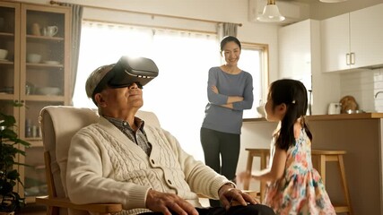 Grandfather wears virtual reality headset. Granddaughter reaches with joy. Woman watches from kitchen smiling. Family explores technology together at home. Senior and child share playful connection.