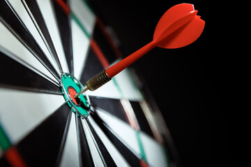 Dart arrow hitting in the target center of dartboard