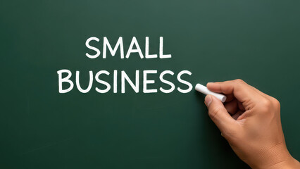 Hand writing small business text on green chalkboard with white chalk.