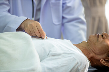 an elderly patient lying on a hospital stretcher receiving emergency medical treatment. Healthcare professionals in medical uniforms are using a manual resuscitator (Ambu bag) to provide assisted vent