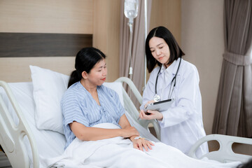 A female doctor uses a stethoscope to check a patient&rsquo;s heartbeat while she lies in a hospital bed, showing care, trust, and professionalism in a healthcare environment.