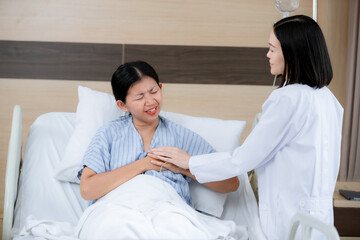 female patient lying in a hospital bed, appearing to be in pain as she clutches her chest with a pained expression. A doctor stands beside her, gently holding her hand and offering support while asses