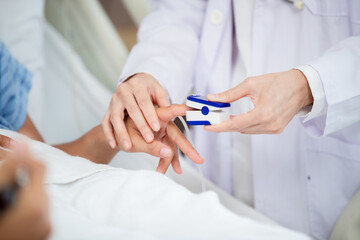 doctor placing a pulse oximeter on a patient's finger to measure oxygen levels and heart rate. The close-up shot focuses on the hands of both the doctor and the patient,
