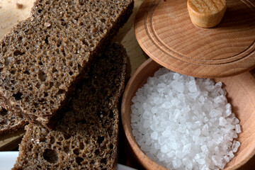 Dark bread and coarse salt on a rustic wooden table at lunchtime