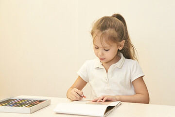 Naklejka premium Young caucasian female child drawing with colored pencils in a calm indoor setting.