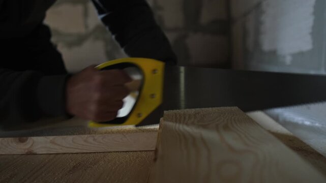 Wood floor installation, hand sawing lumber plank during DIY construction, Close-up