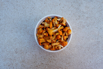 Closeup top view of white bowl with golden chanterelle (Cantharellus cibarius) wild edible mushrooms