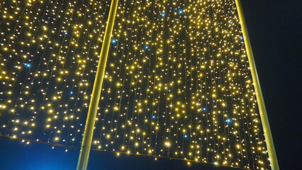 Flashing yellow and blue modern garlands of light bulbs in evening darkness. Theme of the New Year and Christmas. A background of sparkling light bulbs. Festive mood. Window and street decoration