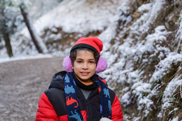 Caucasian Child Aged Ten Wearing Earmuffs and Hat Looking at Camera on a Winter Day