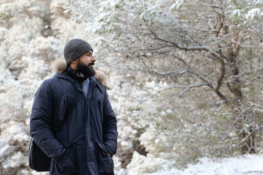 Photograph of a Forty-Year-Old Man with a Long Black Beard in a Frozen Snowy Winter Landscape Wearing a Coat
