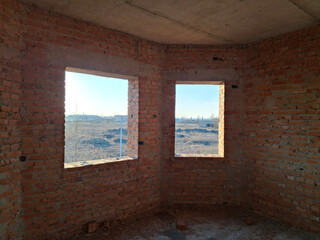 Interior of an unfinished cottage with brick walls and two windows