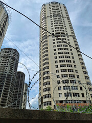 Unfinished skyscrapers are surrounded by fence with barbed wire