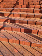 Stair. Metal steps on the bridge. Red iron steps with a shadow from the railing