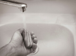 male hand with the soap under water tap in wash-sink