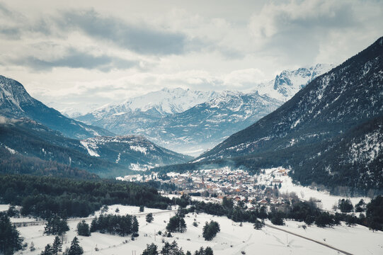 Snowy winter panorama of an alpine valley with mountains and the village of La Vachette on the road to Brian&ccedil;on in the French Alps