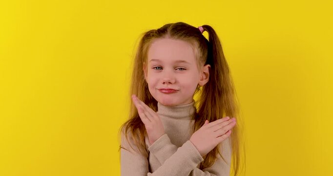 4K stock footage of a Caucasian girl making a &ldquo;no&rdquo; gesture and shaking her head against a bright yellow background. The clear and expressive body language conveys refusal, disagreement, denial, or rej